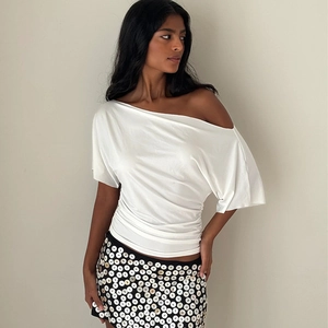 Haut moulant blanc à une épaule froncée avec jupe noire à boutons pour l'été