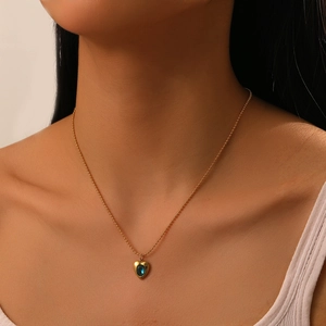 Close-up of a gold stainless steel chain with a blue gemstone heart pendant on a model
