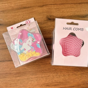 Front and back detail of pink star-shaped unicorn hair combs in plastic packaging
