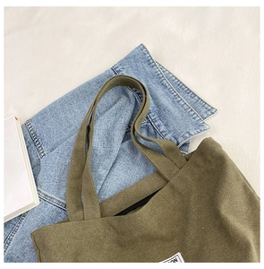 Detail of olive green canvas tote bag showing zipper closure and durable cotton texture