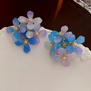 Boucles d'oreilles fleurs en acrylique dégradé bleu et violet avec perles sur plat blanc