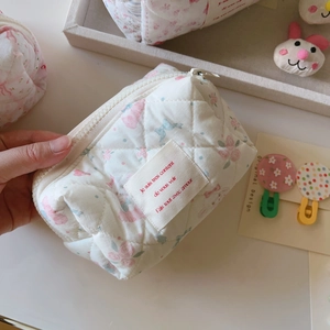 Détail de la trousse à maquillage matelassée avec motif floral, lapin et texture souple
