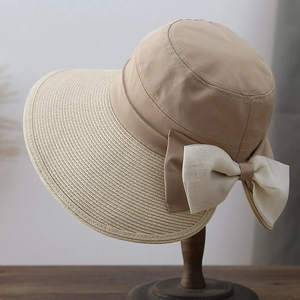 Detail of a straw sun hat featuring a delicate white chiffon bow and woven texture
