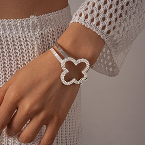 Dettaglio del bracciale a polsino con quadrifoglio in strass su polso femminile
