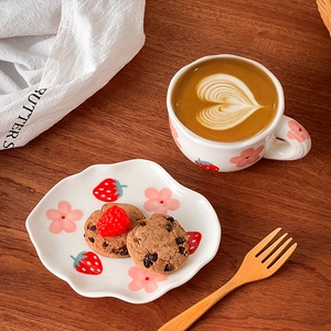 Top-down view of a ceramic cup and cloud-shaped saucer with hand-painted floral patterns