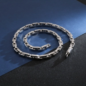 Macro detail of silver stainless steel chain necklace with unique square clasp design