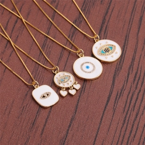 Four gold necklaces with white enamel Evil Eye pendants on a rustic brown wood background