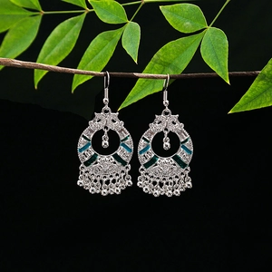 Close-up of ethnic silver alloy earrings with blue enamel detailing and bell tassels