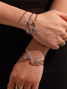 Gros plan de bracelets étoile de mer dorés 18k et de bagues avec pierres colorées