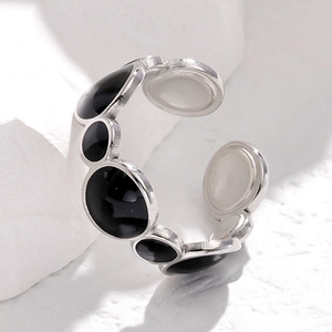 Detail of silver stainless steel open ring featuring black enamel circles on white stone