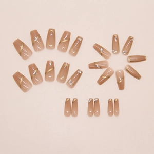 Détail de 24 faux ongles perle miel avec dégradé marron et lignes dorées élégantes