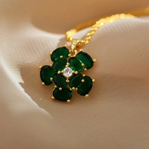 Macro detail of a gold flower necklace featuring emerald green petals and a zircon center