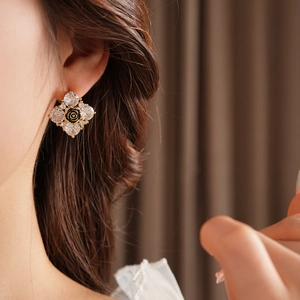 Dettaglio orecchini a fiore placcati oro con cristalli sul lobo per un look di lusso