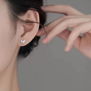 Macro shot of 925 sterling silver butterfly stud earring worn on the earlobe