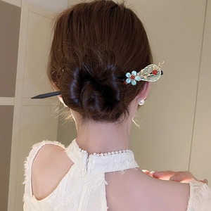 Detail view of a Chinese wooden hairpin with blue flowers and tassels in a bun hairstyle