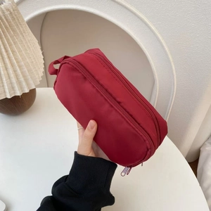 Detail of burgundy double-layer nylon pouch with sturdy handle held by hand