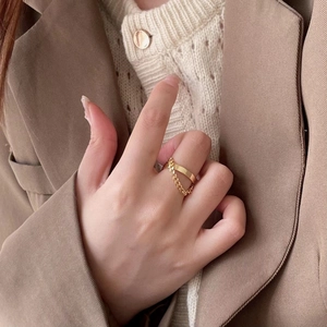 Detailed close-up of a golden Cuban chain ring worn by a model in soft earth tones