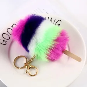 Close-up of a colorful popsicle-shaped plush keychain with faux fur stripes and gold metal clasp
