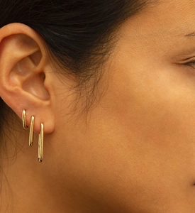 Three gold U-shaped paperclip earrings in small, medium, and large sizes on an ear model