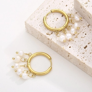 Detailed view of vintage gold hoop earrings with white pearls on a stone background