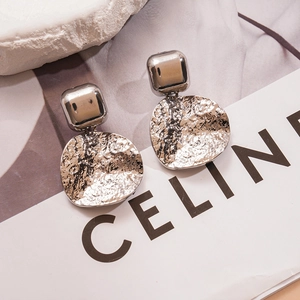 Gros plan de boucles d'oreilles géométriques argentées avec texture martelée unique