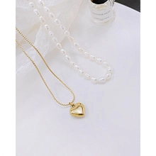Close-up of a 14k gold-plated heart pendant and baroque freshwater pearl necklace