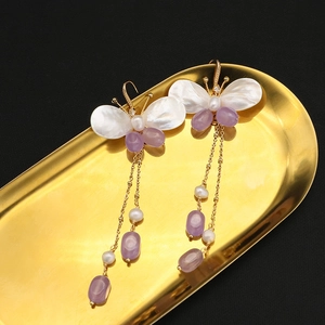 Elegant butterfly drop earrings with purple tassels and pearls on a gold tray