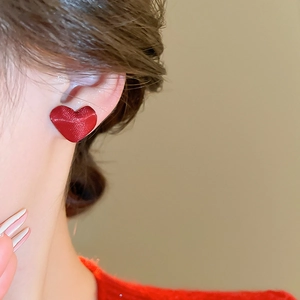 Primo piano di orecchini a lobo a cuore rossi con texture opaca indossati dal modello