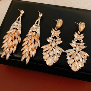 Gros plan de boucles d'oreilles pampilles en cristal champagne sur fond de cuir noir