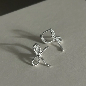 Detailed shot of bow-shaped silver earrings featuring intricate twisted rope texture
