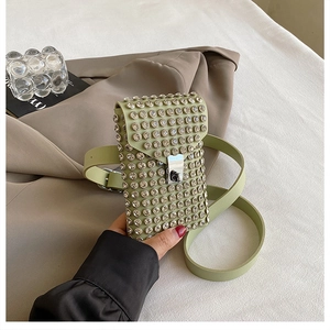 Close-up of light green rhinestone phone bag with leather strap and metal buckle detail