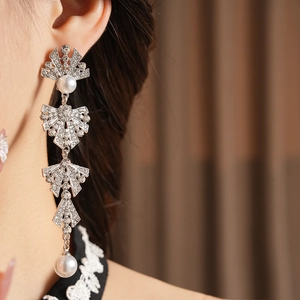 Close-up of silver tassel earrings with pearls and rhinestones on a female model