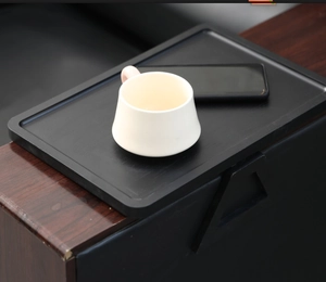 Detail of black wood grain sofa armrest tray with compartments for cup and phone