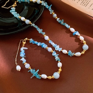 Detailed set of blue aquamarine and pearl necklace with matching bracelet on velvet fabric