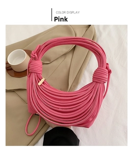Pink knotted shoulder bag with unique woven design and silver zipper closure on a bed