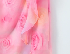 Close-up detail of romantic pink floral rose pattern on lightweight chiffon fabric dress