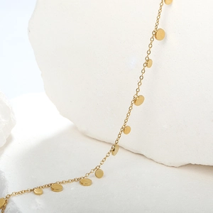 Detailed close-up of gold minimalist chain bracelet featuring tiny circular disc charms
