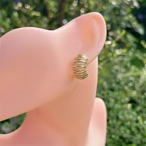 Boucles d'oreilles créoles en C plaquées or 18 carats avec zircons cubiques sur un modèle