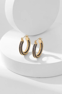 Detailed macro shot of gold hoop earrings featuring three rows of blue zircon pavé crystals