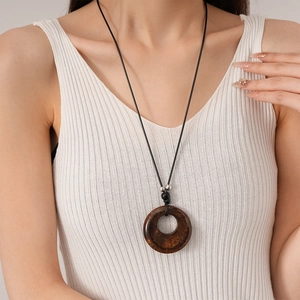 Detail of vintage resin round pendant necklace with marble texture on white knit top