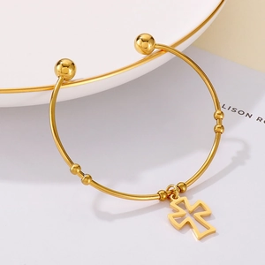 Close-up of gold hollow cross pendant on a stainless steel open beaded bracelet
