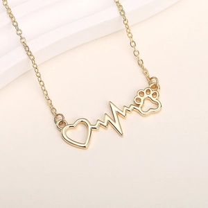 Macro detail of golden heart pendant with cat paw and heartbeat line on a fine chain