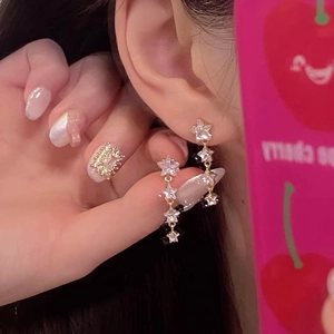 Macro shot of gold star-shaped earrings and crystal pavé ring with luxury details