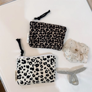 Detail of leopard print cotton pouches with zipper pull and woven brand label