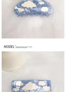 Detail of blue acetate hair claw and clip with marble clouds on white fabric