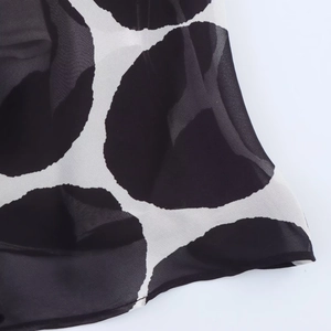 Dettaglio macro del tessuto in chiffon leggero con stampa a pois bianchi e neri
