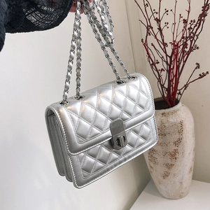 Silver quilted chain bag with metallic PU leather and turn-lock closure held by hand