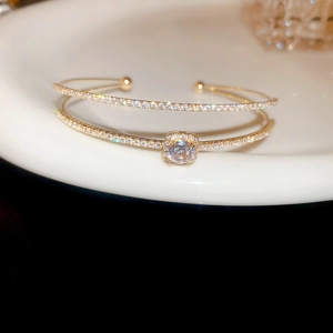 Macro shot of rose gold double-layer open bangle with square zircon stone and pave accents