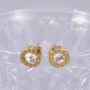 Vue macro de boucles d'oreilles chiffres romains dorées avec zircon scintillant central