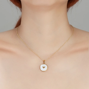 Gold titanium necklace with round shell pendant and tiny heart on a professional model